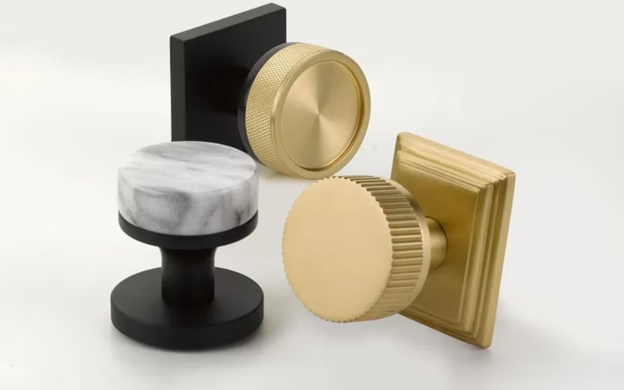 Close-up of three different cabinet knobs: black, marble, and brass finishes on a white background. Close-up of three different cabinet knobs: black, marble, and brass finishes on a white background.