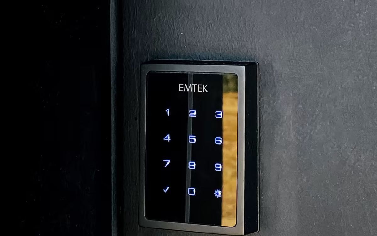 A close-up of a digital keypad door lock on a black surface. The keypad displays illuminated numbers. A close-up of a digital keypad door lock on a black surface. The keypad displays illuminated numbers.