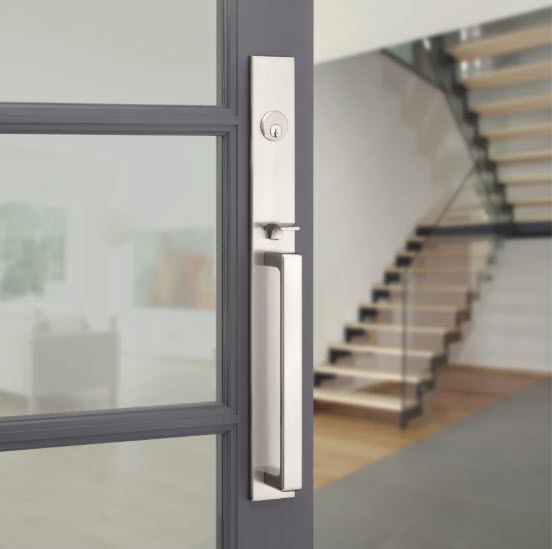Brushed nickel door handle on a gray door with interior staircase in background. Brushed nickel door handle on a gray door with interior staircase in background.