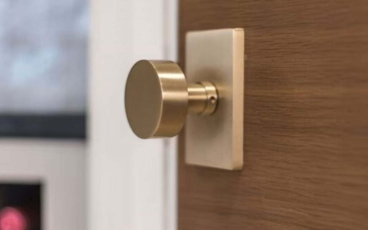 Gold-toned door knob and plate on a wooden door. Gold-toned door knob and plate on a wooden door.