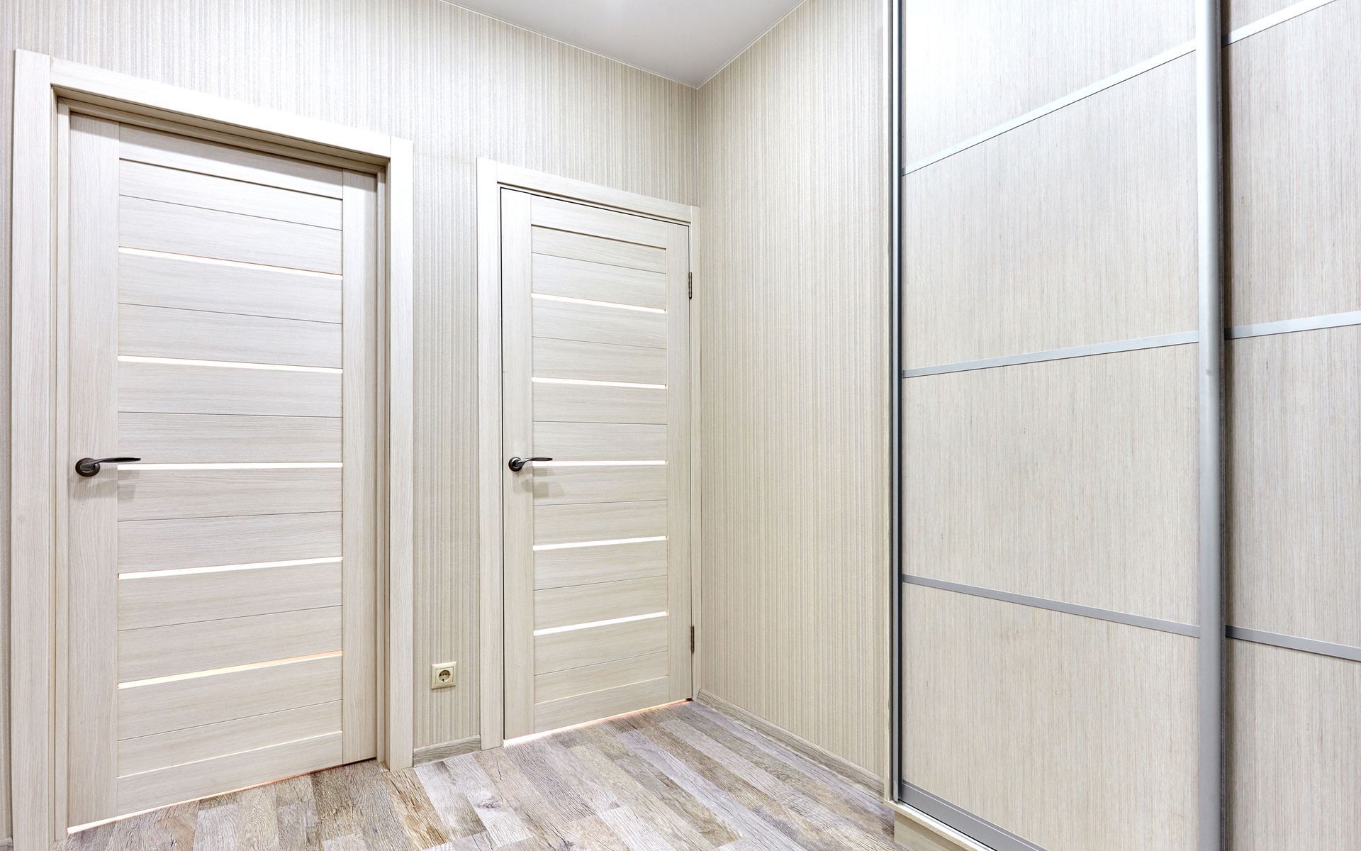 Light-colored room with two doors and a sliding closet. Light wood-look walls and floor. Light-colored room with two doors and a sliding closet. Light wood-look walls and floor.