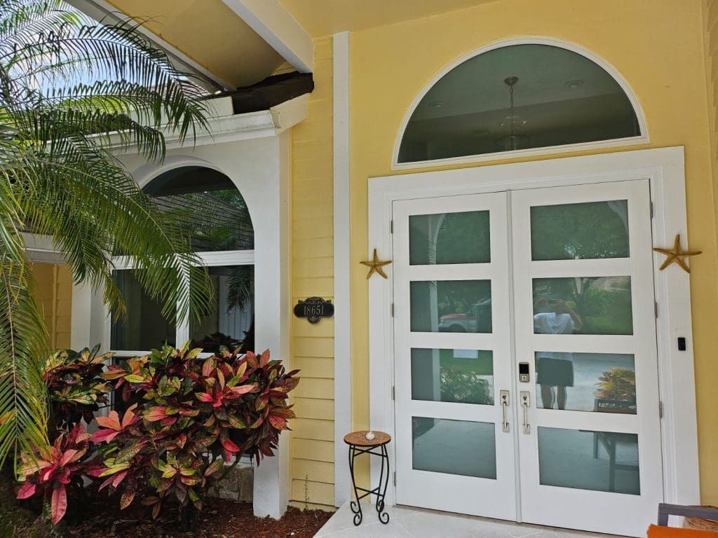 Yellow house entrance with arched window and double doors. White trim, star accents.