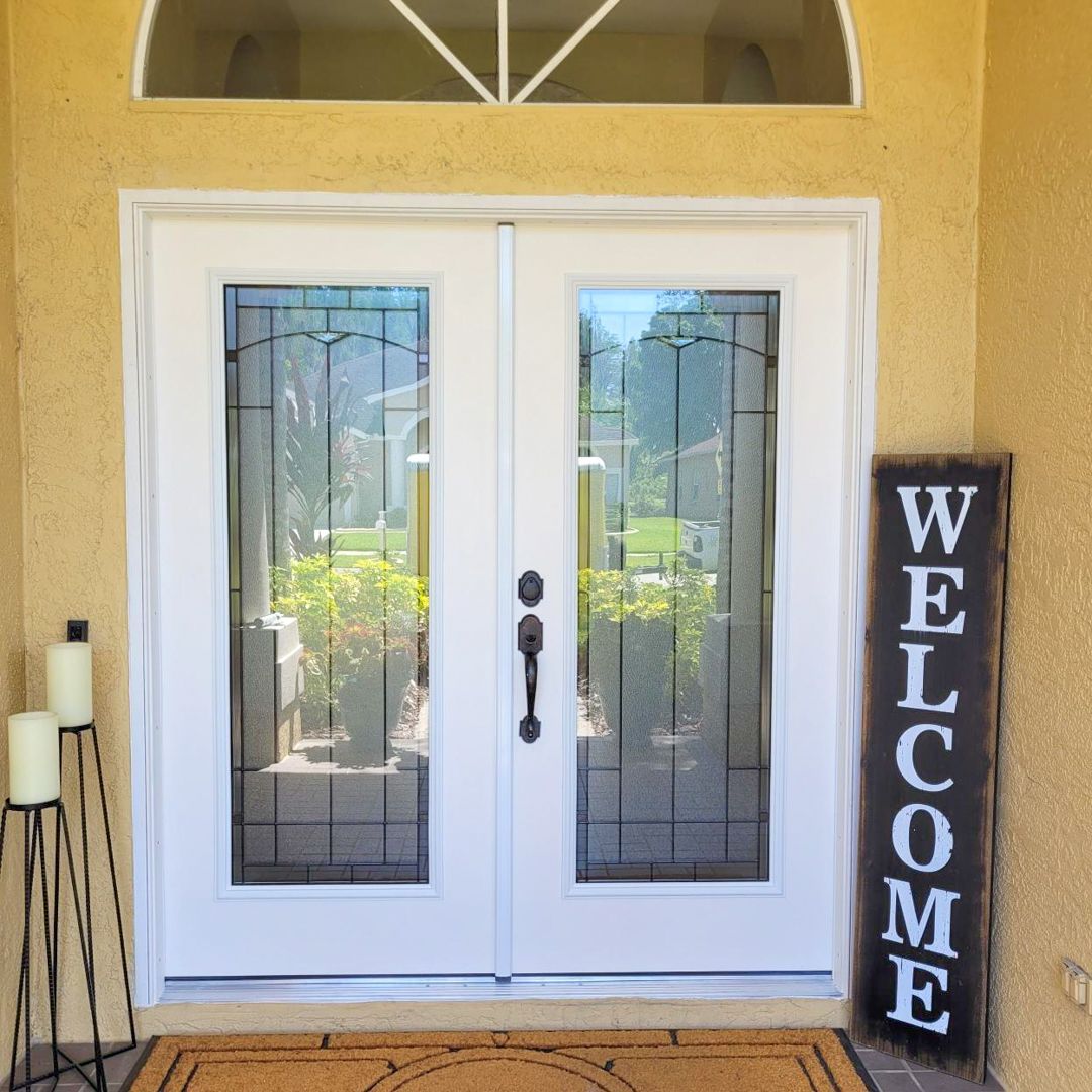 White double doors with glass panels and a welcome sign in front.
