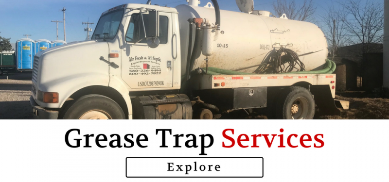 A white industrial vacuum truck for grease trap services parked outside, with an