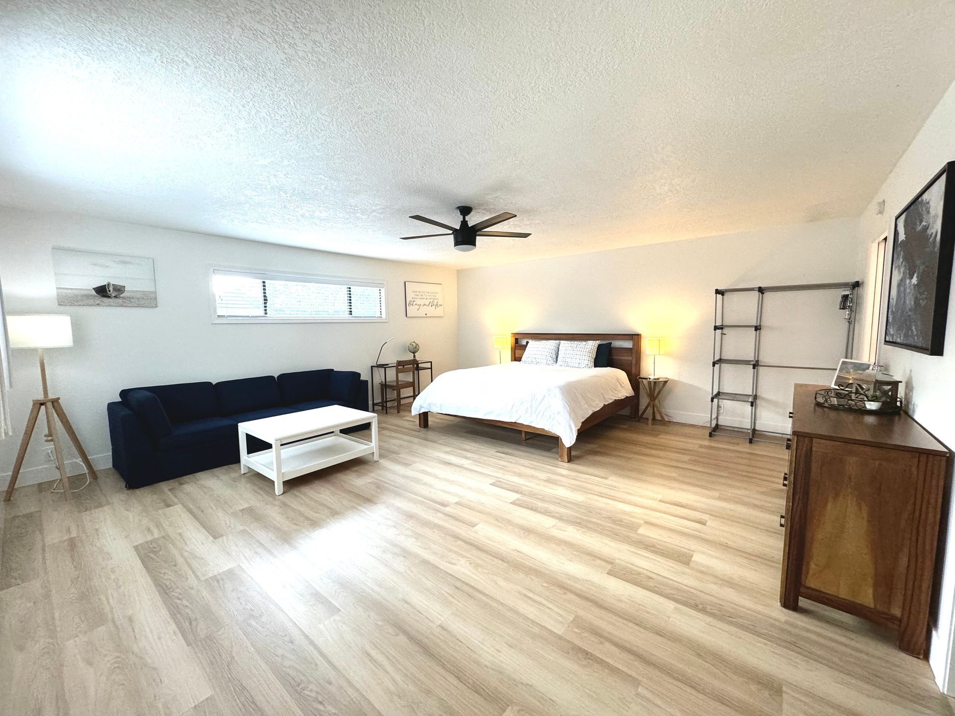 A living room with a bed , couch , coffee table and dresser.