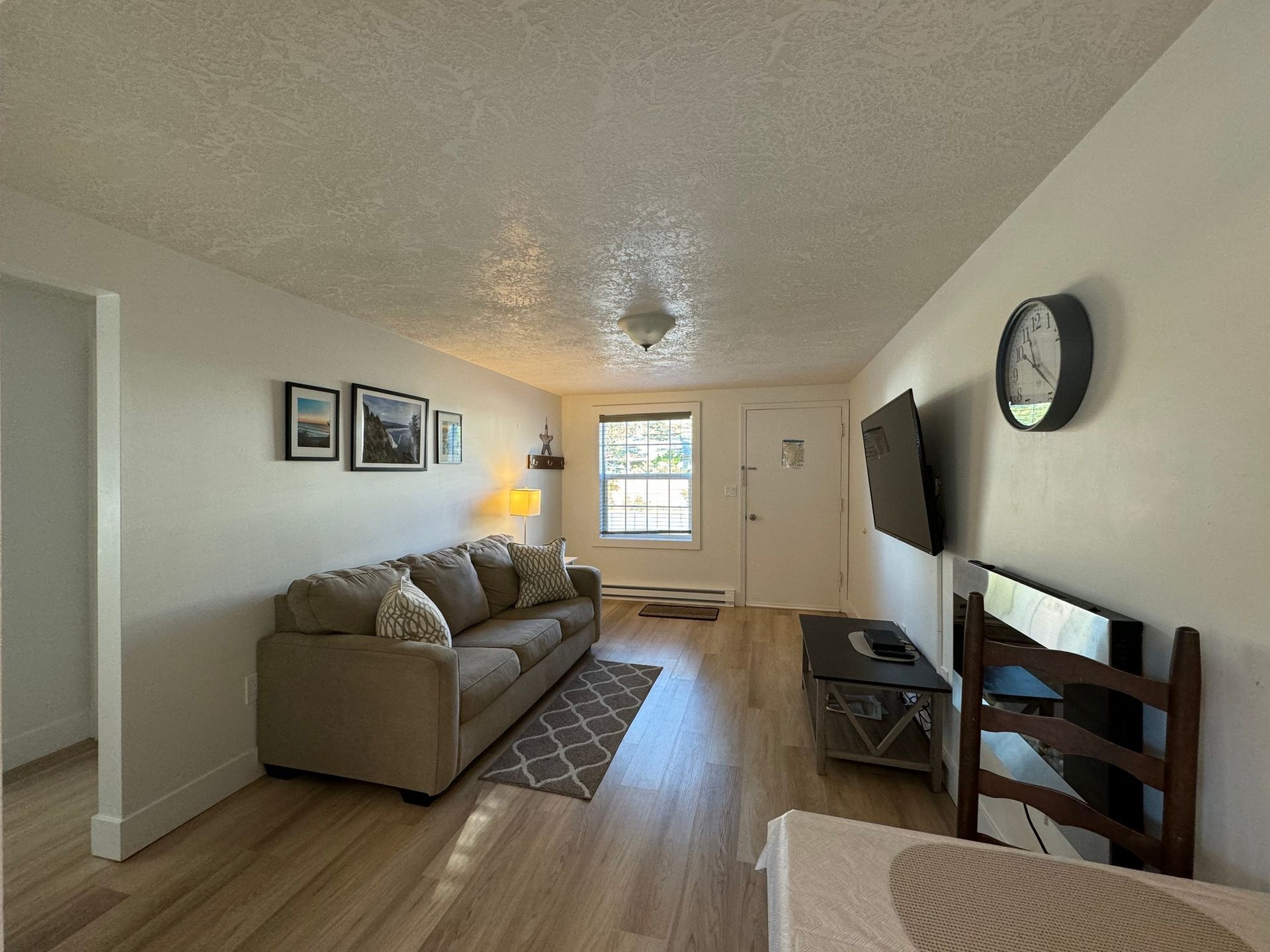 A living room with a couch , television and a clock on the wall.