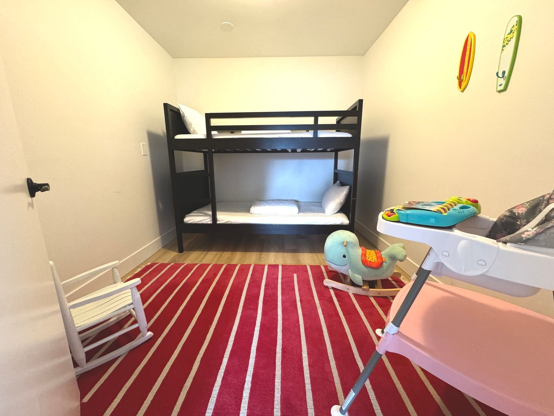 A bedroom with bunk beds a rocking chair and a changing table