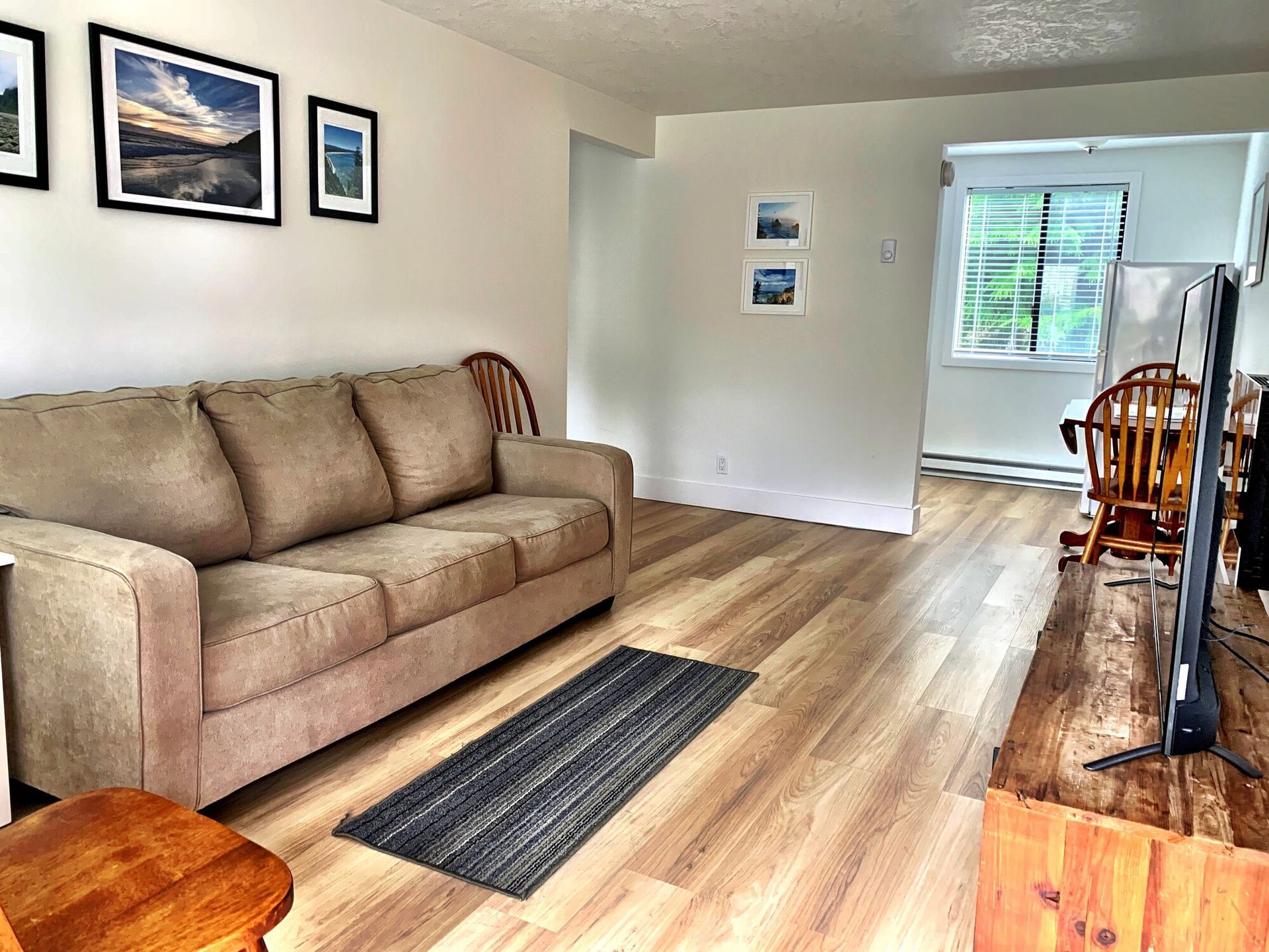A living room with a couch , chairs , and a flat screen tv.