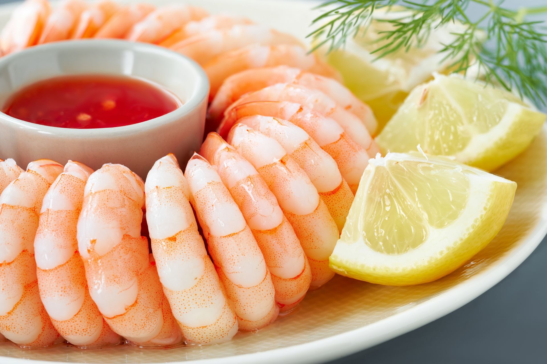 A white plate topped with shrimp , lemon slices and sauce.