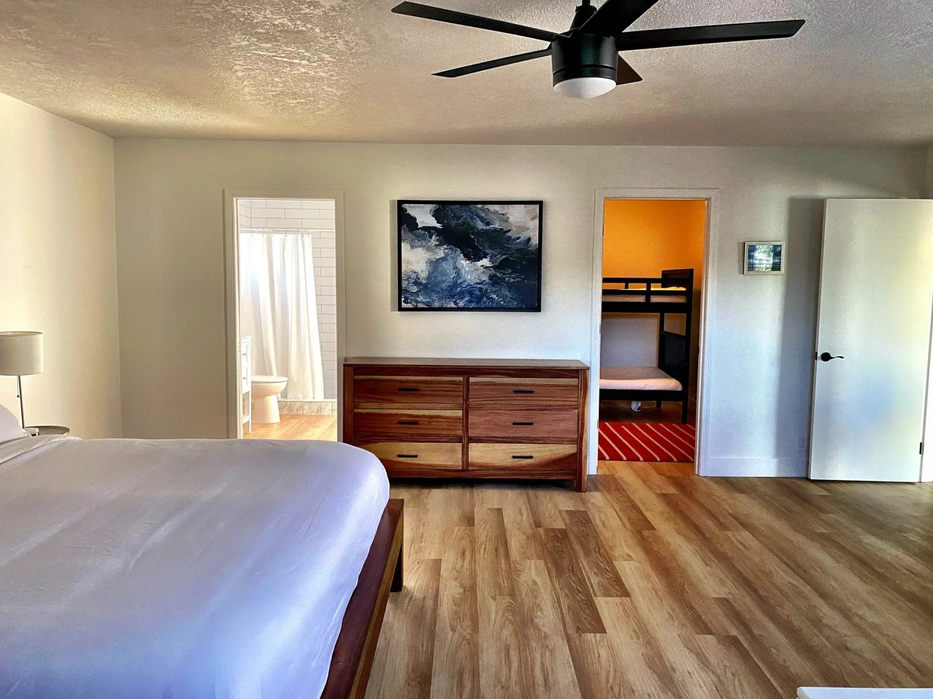 A bedroom with a bed , dresser , and ceiling fan
