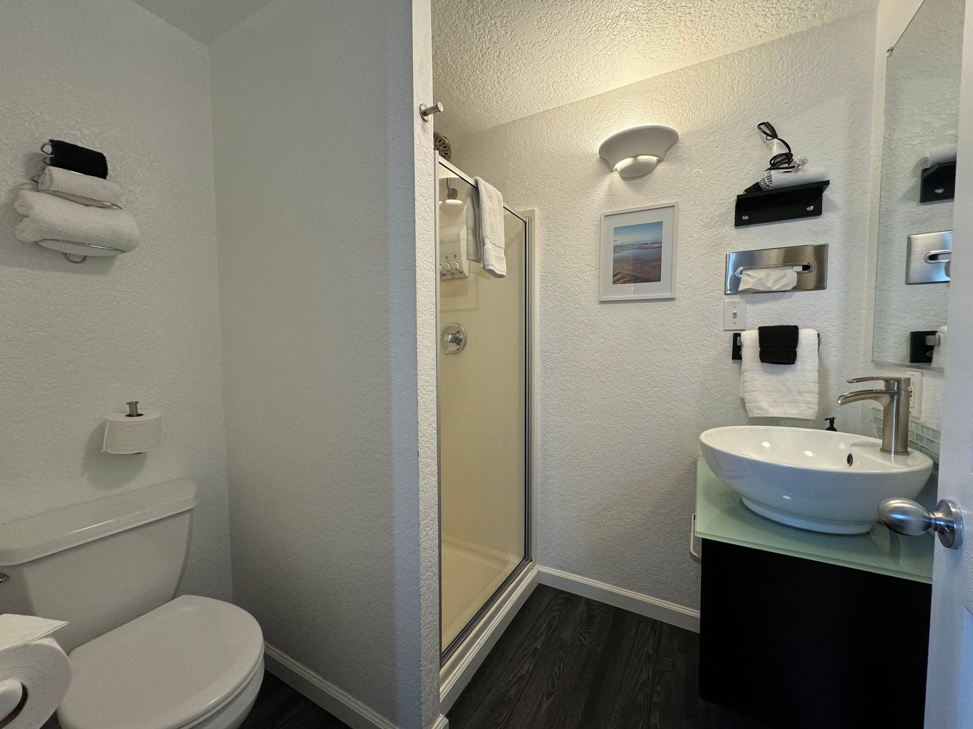 A bathroom with a toilet , sink and shower.