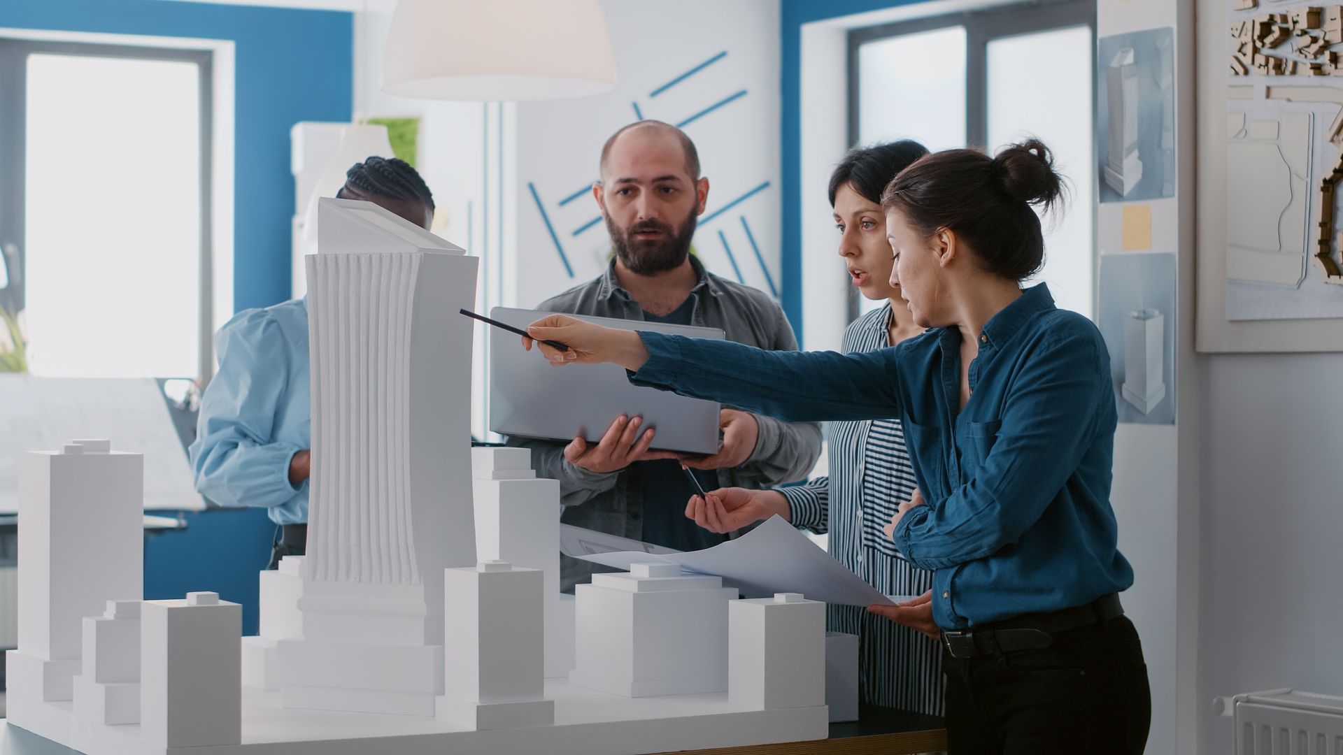 Team reviewing a white architectural model in a bright office studio