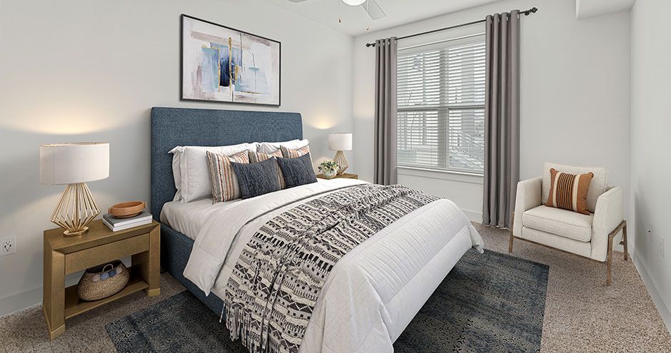 Bedroom with blue upholstered bed, beige chair, window, and nightstand at The Standard at Domain NORTHSIDE, offers luxury apartments in North Austin.