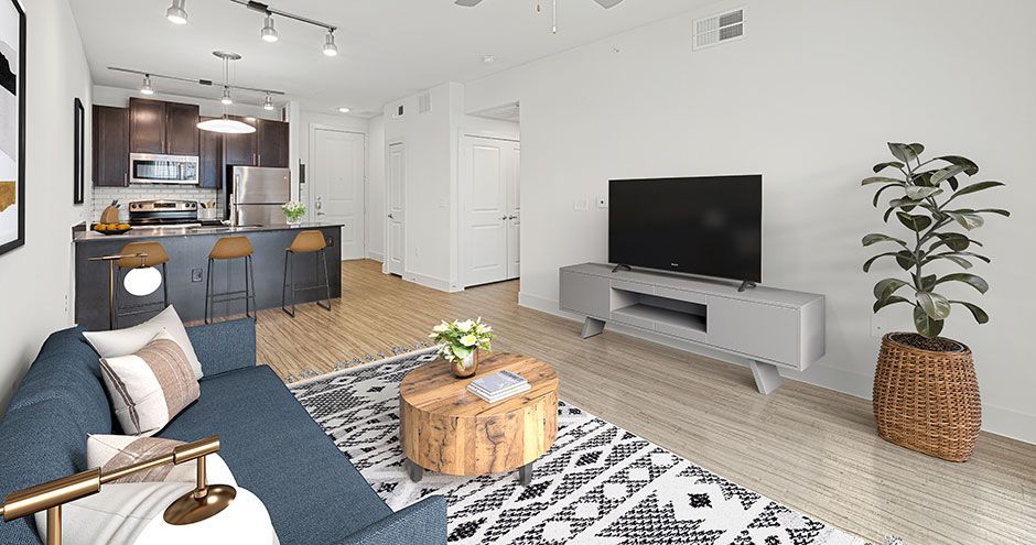 Modern living room with a blue sofa, TV, and kitchen in the background at The Standard at Domain NORTHSIDE, offers furnished apartments in North Austin.