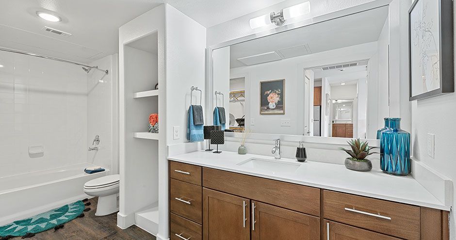 Bathroom with white walls, brown vanity, large mirror, and a shower/tub combo at The Standard at Domain NORTHSIDE, offers apartments near The Domain Austin.