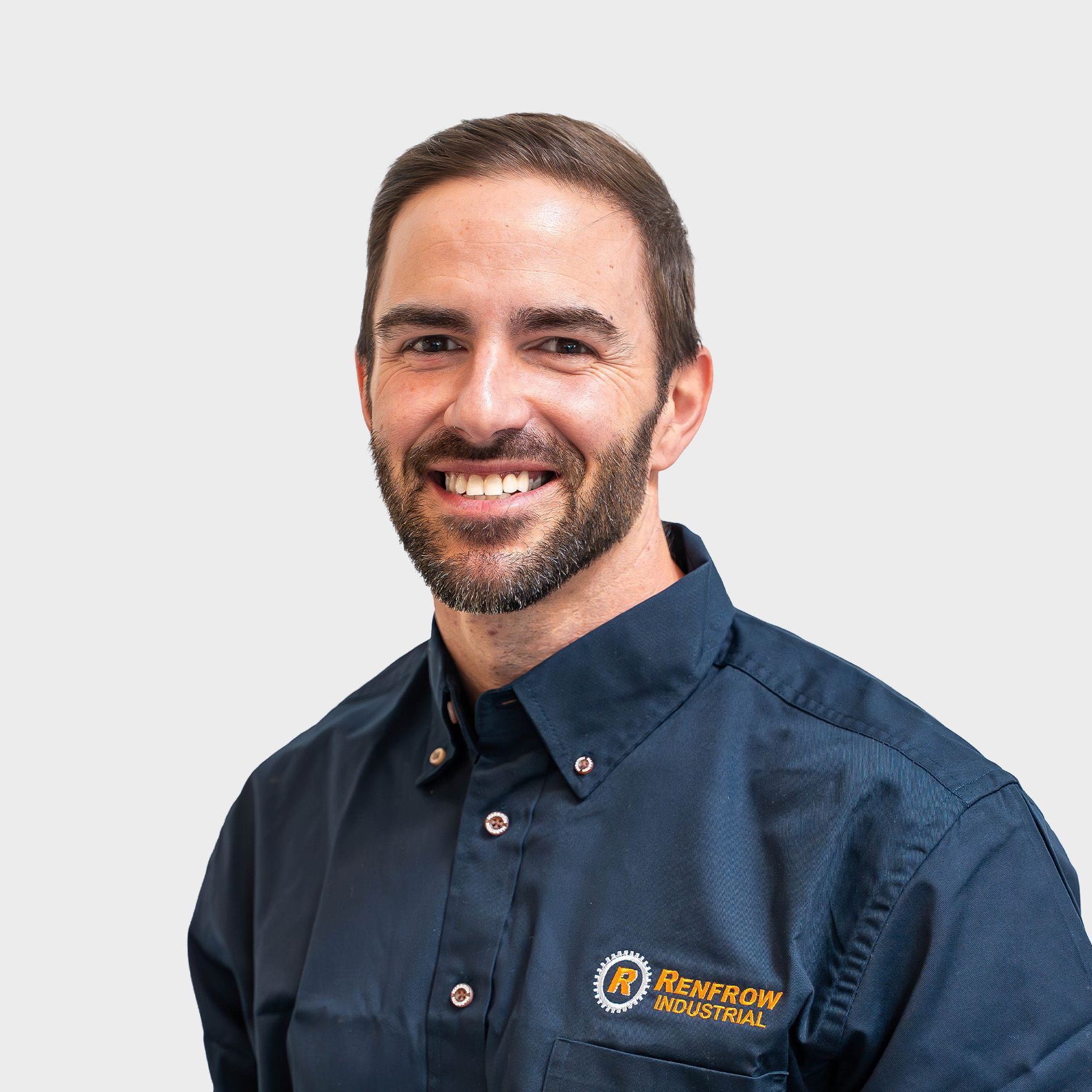 Man with glasses, smiling, wearing a navy polo shirt, against a white background.