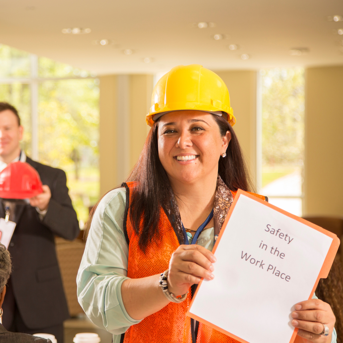 Woman in hard hat and vest holds