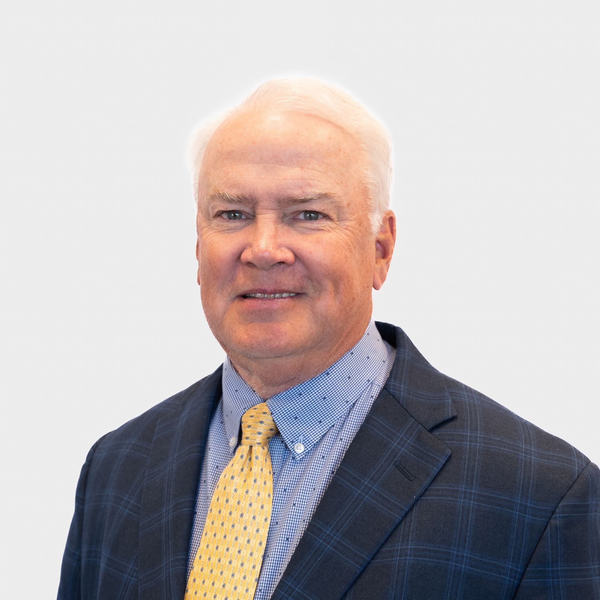 A man in a suit with a yellow tie smiles at the camera.