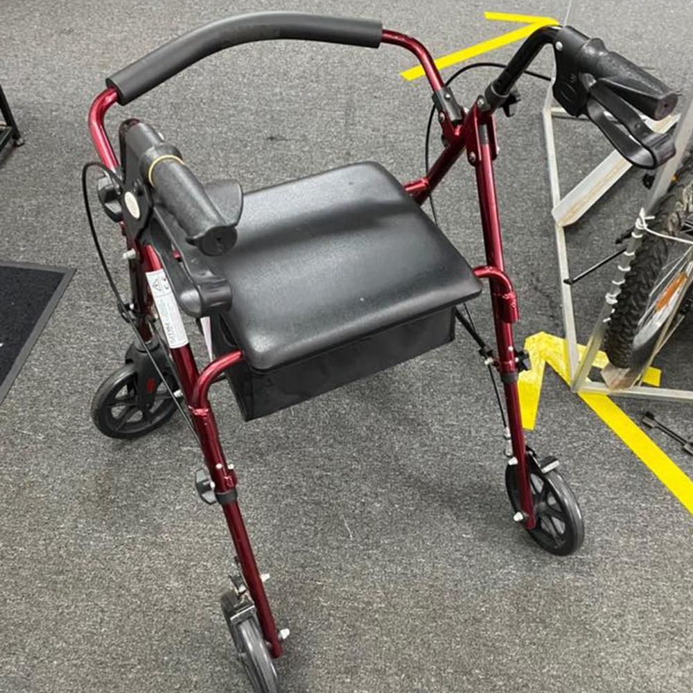 A Red Walker Is Sitting on The Floor Next to A Bike — Toukley World of Bikes In Toukley, NSW