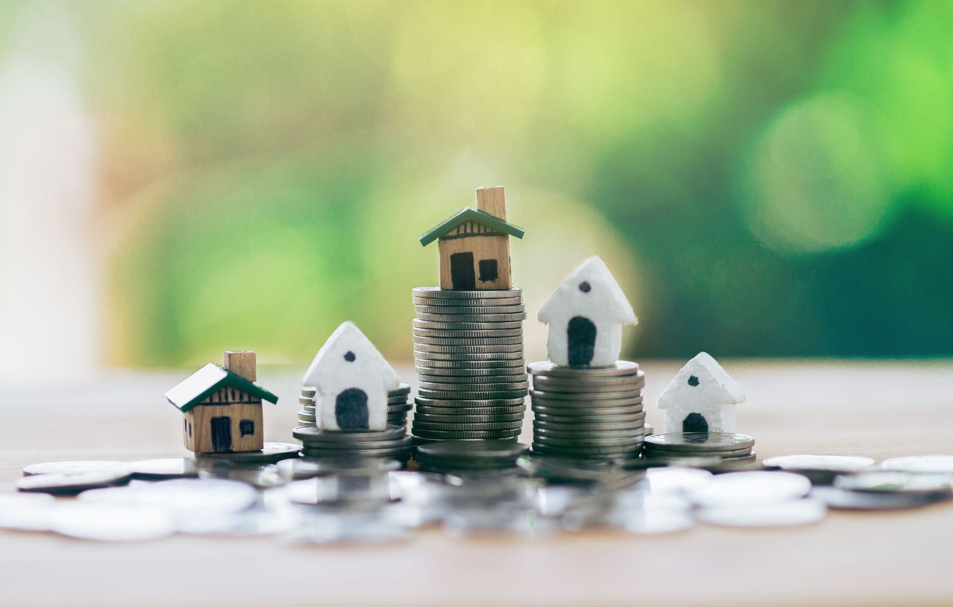 A group of houses sitting on top of stacks of coins on a table.