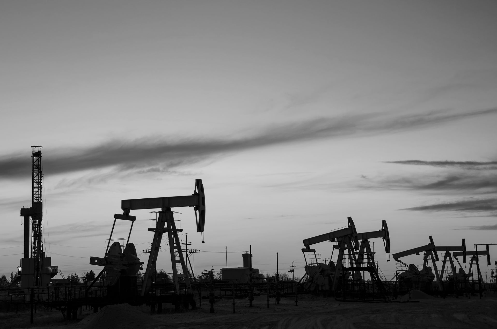 A black and white photo of oil pumps in a field