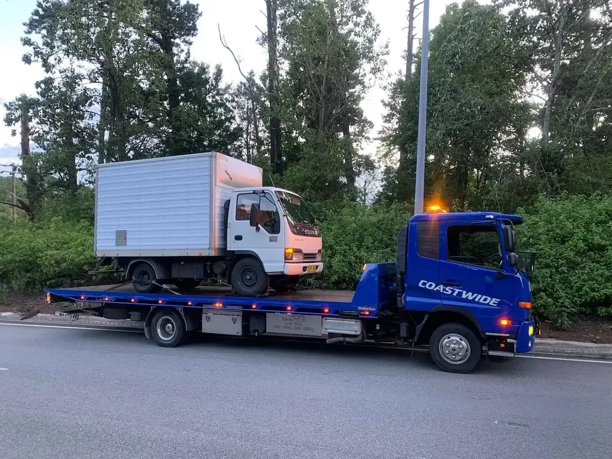 A Blue Tow Truck is towing away a truck — Coastwide Towing & Transport In Berkeley Vale, NSW