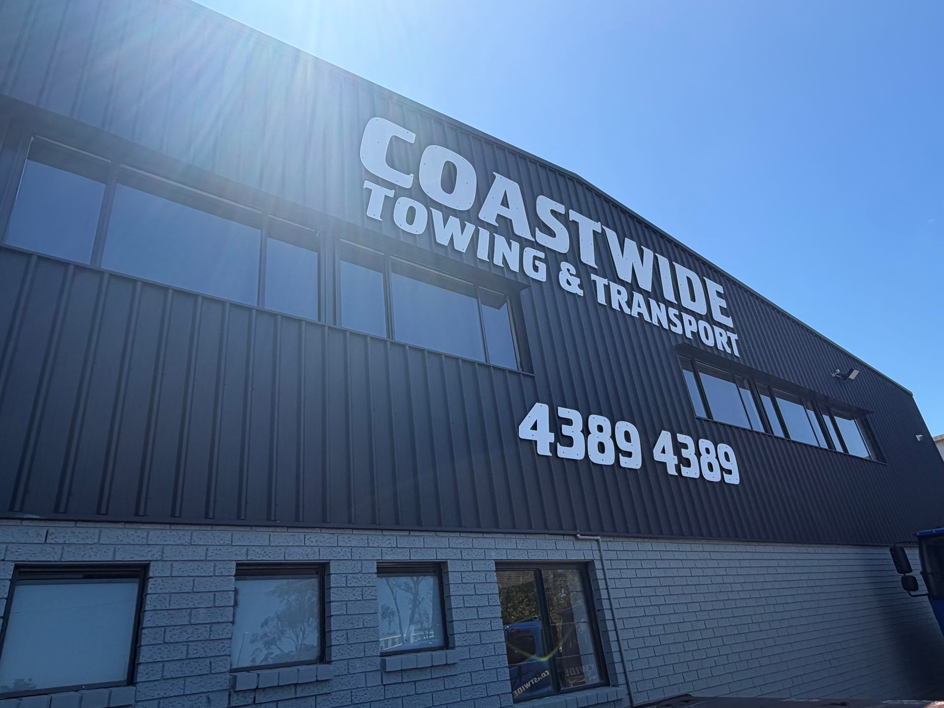 Coastwide Towing & Transport building with phone number 4389 4389 against a blue sky. — Coastwide Towing & Transport In Berkeley Vale, NSW