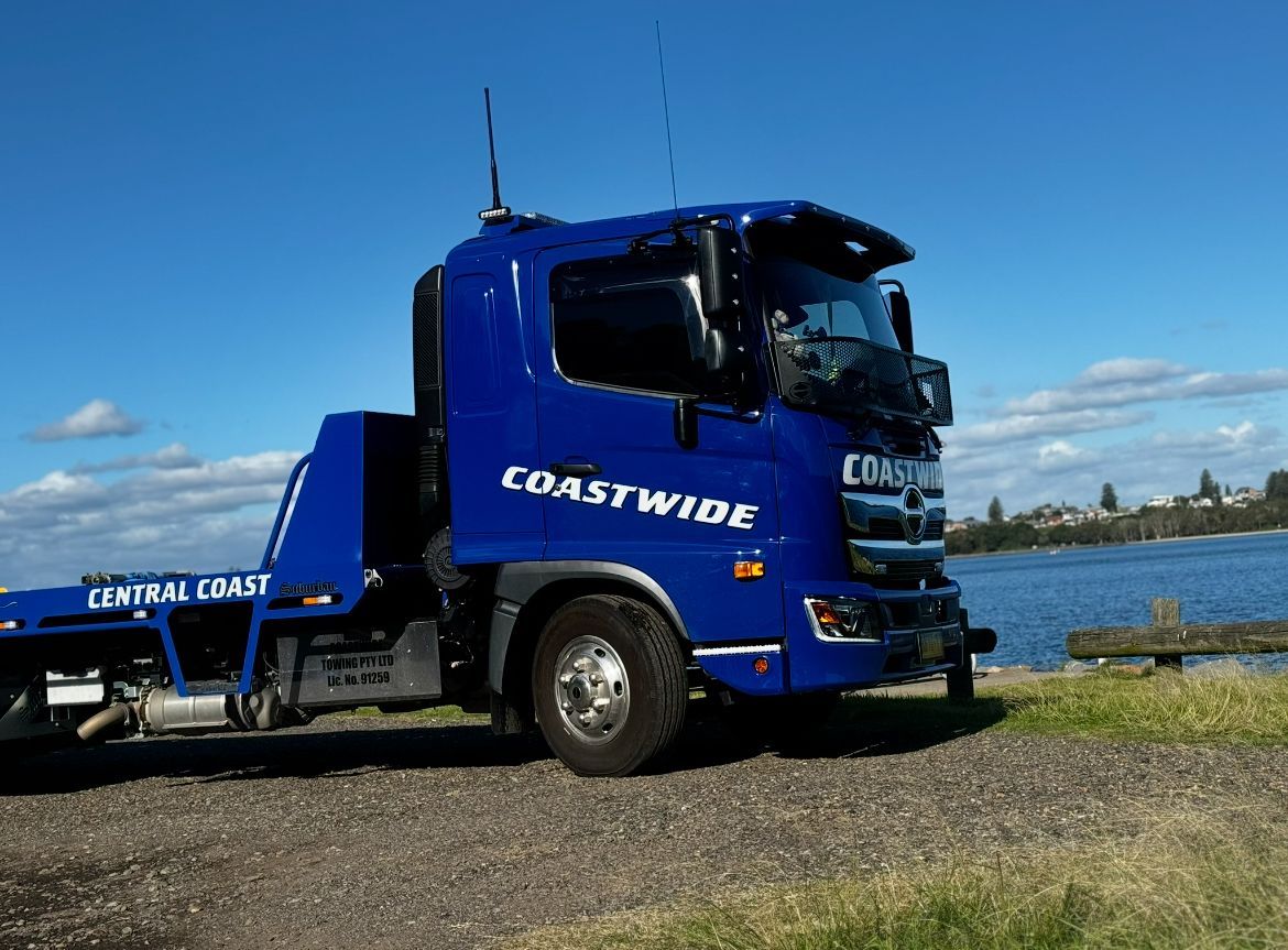A Blue Coastwide Tow Truck Is Parked On The Side Of The Road — Coastwide Towing & Transport In Singleton, NSW