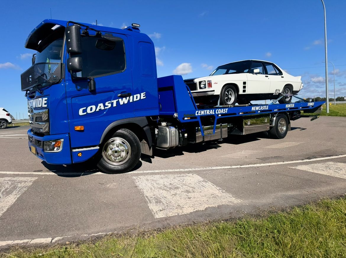 An Old Car Is Sitting On Top Of A Tow Truck — Coastwide Towing & Transport In Berkeley Vale, NSW