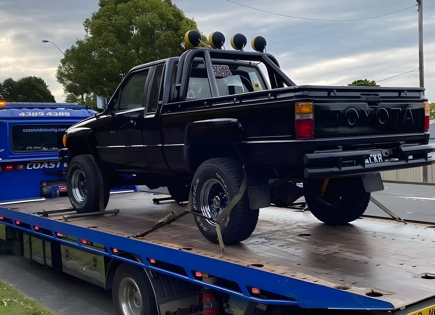 A Black Toyota Pickup Truck Being Transported On A Flatbed Tow Truck