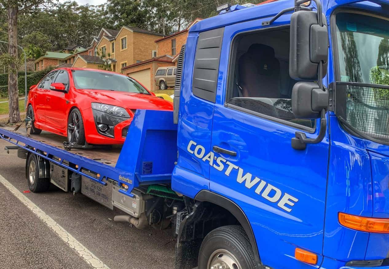 A Red Car Is Being Towed By A Blue Tow Truck — Coastwide Towing & Transport In Berkeley Vale, NSW