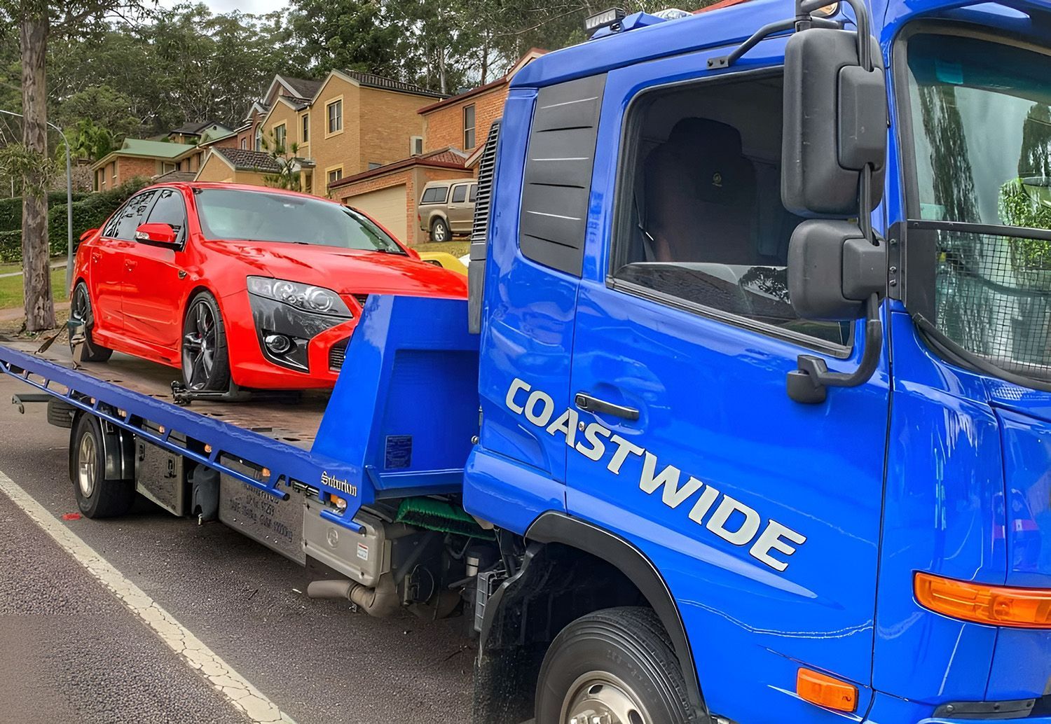 Red Car Being Towed On A Blue Coastwide Towing & Transport Truck