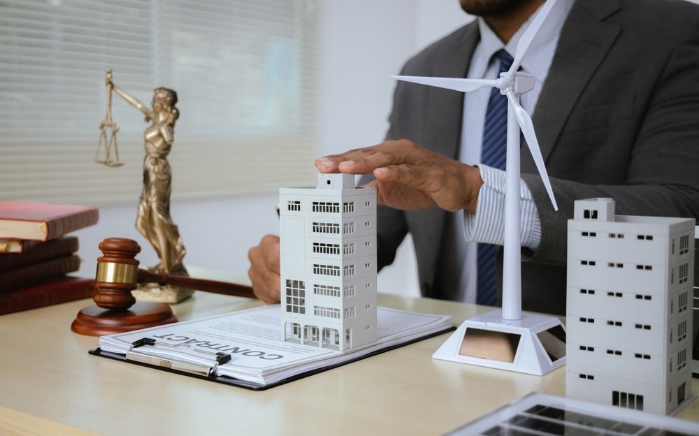 Businessman reviewing a legal case with model buildings, scales, and a gavel on a desk