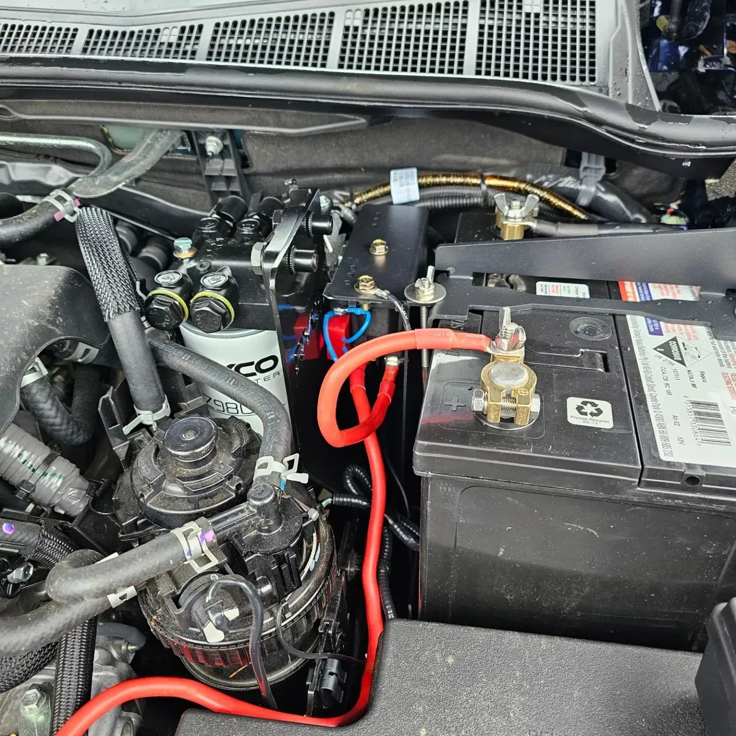 Car Engine Bay with Black Battery and Red Jumper Cables Connected — Bay City A1 Tyres in North Geelong, VIC