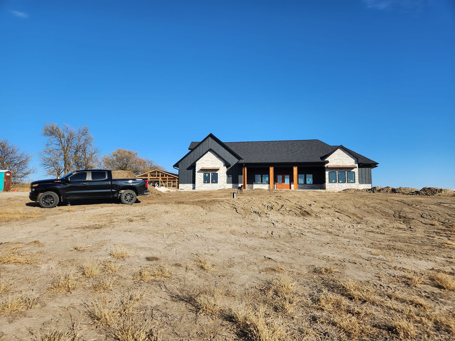A black truck is parked in front of a house in a field. Independence Built Custom Home Builder in Nebraska