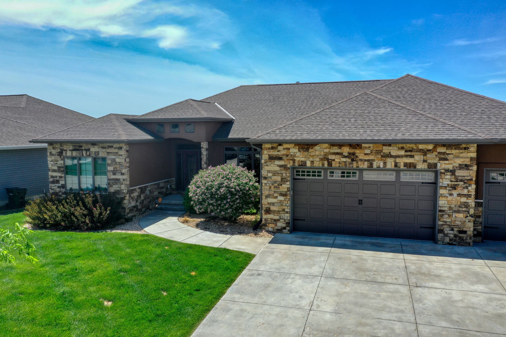 A house with a large garage and a stone wall is for sale.