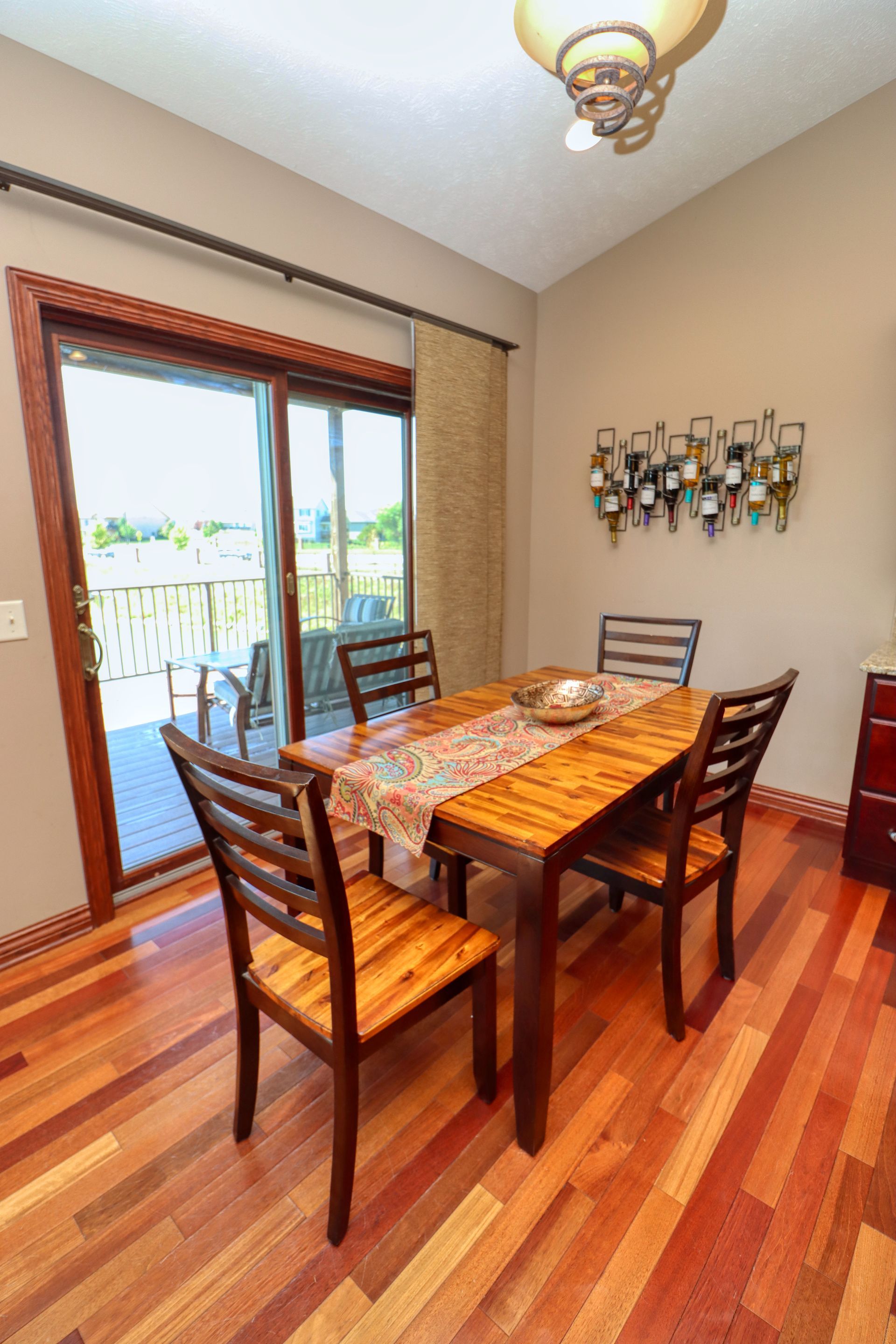 A dining room with a wooden table and chairs and a sliding glass door.