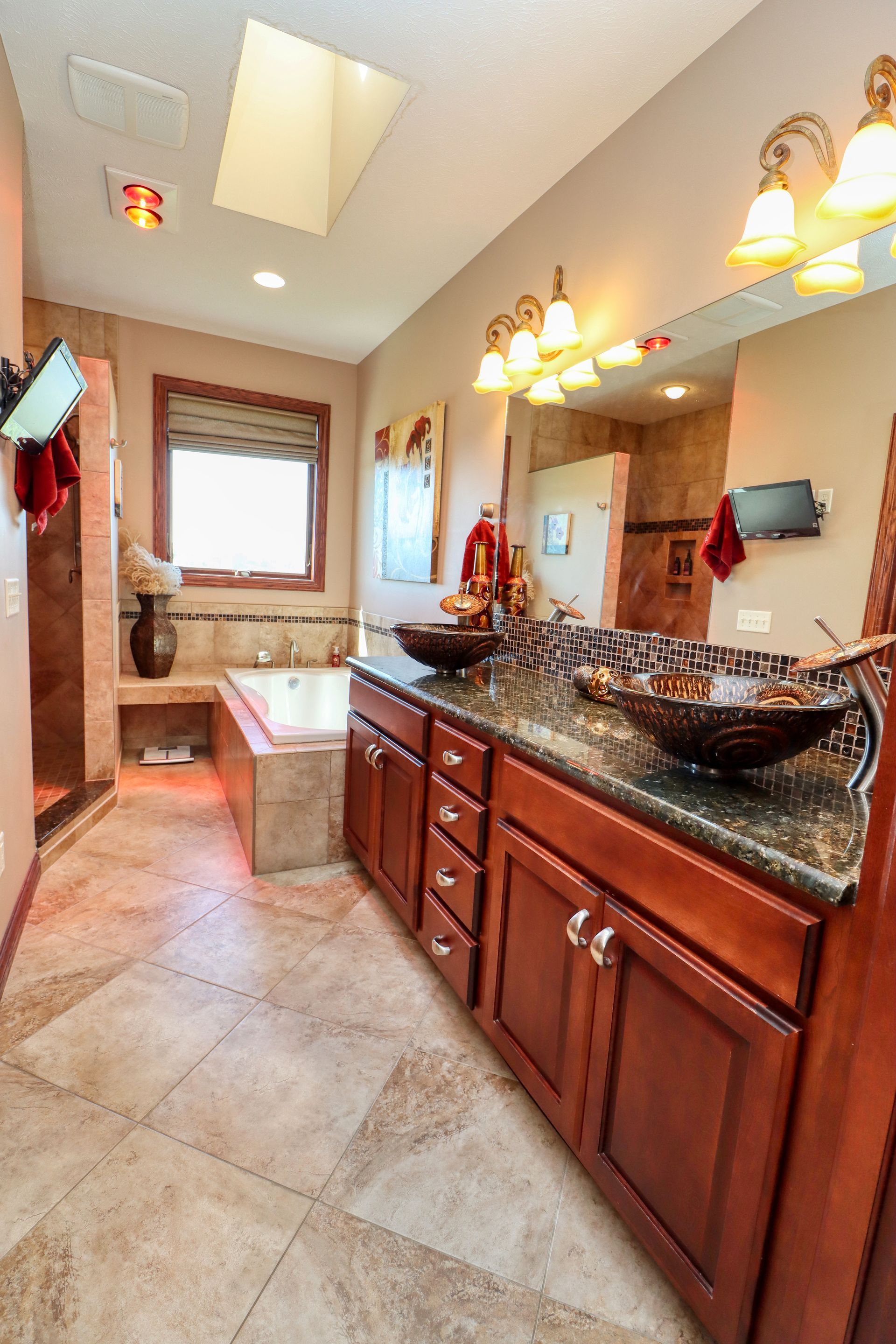 A bathroom with two sinks , a tub , and a large mirror.