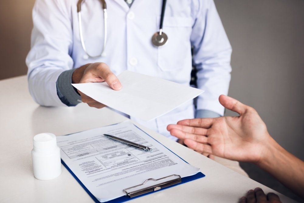 Male Doctor Talking In Clinic Room And Handing A Prescription To The Patient — Deception Bay Doctors In Deception Bay, QLD