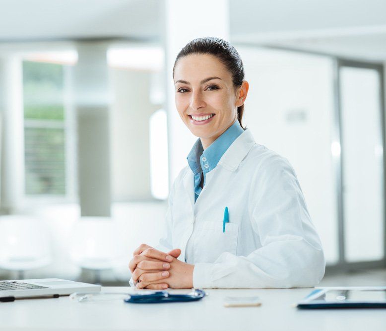 Female Doctor Working At Office Desk And Smiling At Camera — Deception Bay Doctors In Deception Bay, QLD