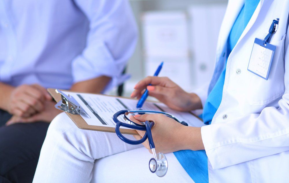 Female Doctor Sitting With Male Patient At The Desk — Deception Bay Doctors In Deception Bay, QLD