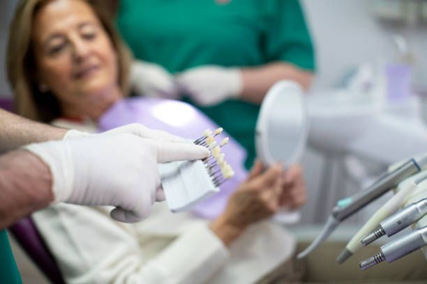 Dentist and patient selecting tooth color for dental implants in modern dental clinic setting.