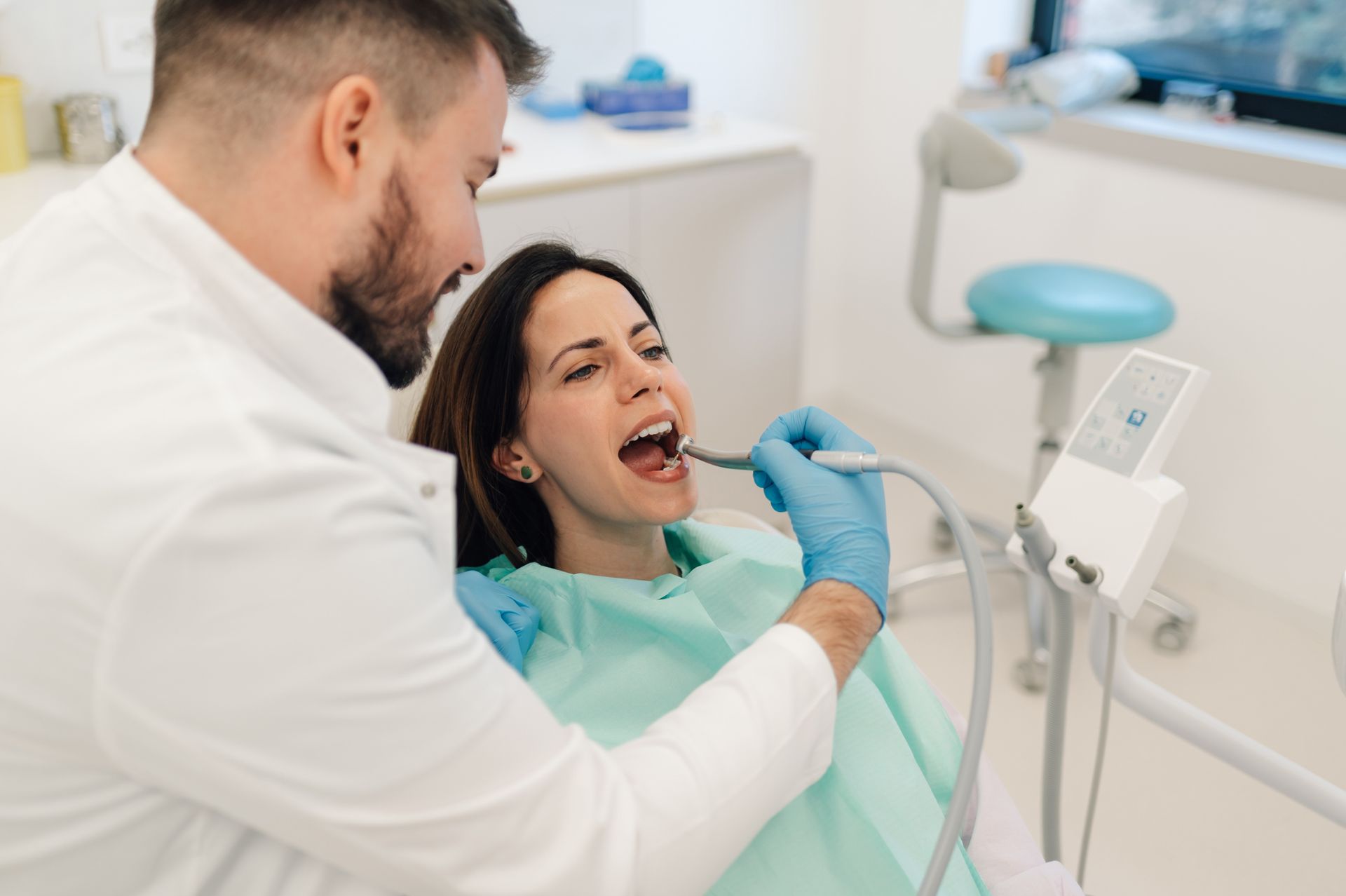 Dentist using dental drill on patient in dental clinic.
