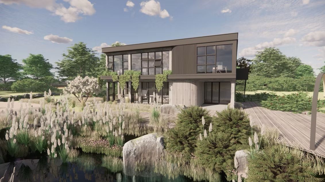 Modern house with large windows overlooks a lake, lush greenery in foreground.