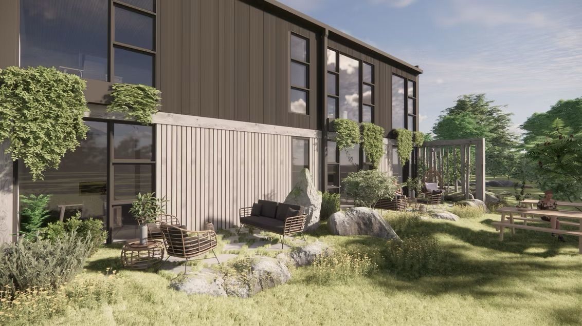 Maison moderne à deux étages avec revêtement extérieur foncé. Grandes fenêtres, aménagement paysager avec rochers et bancs dans la cour.