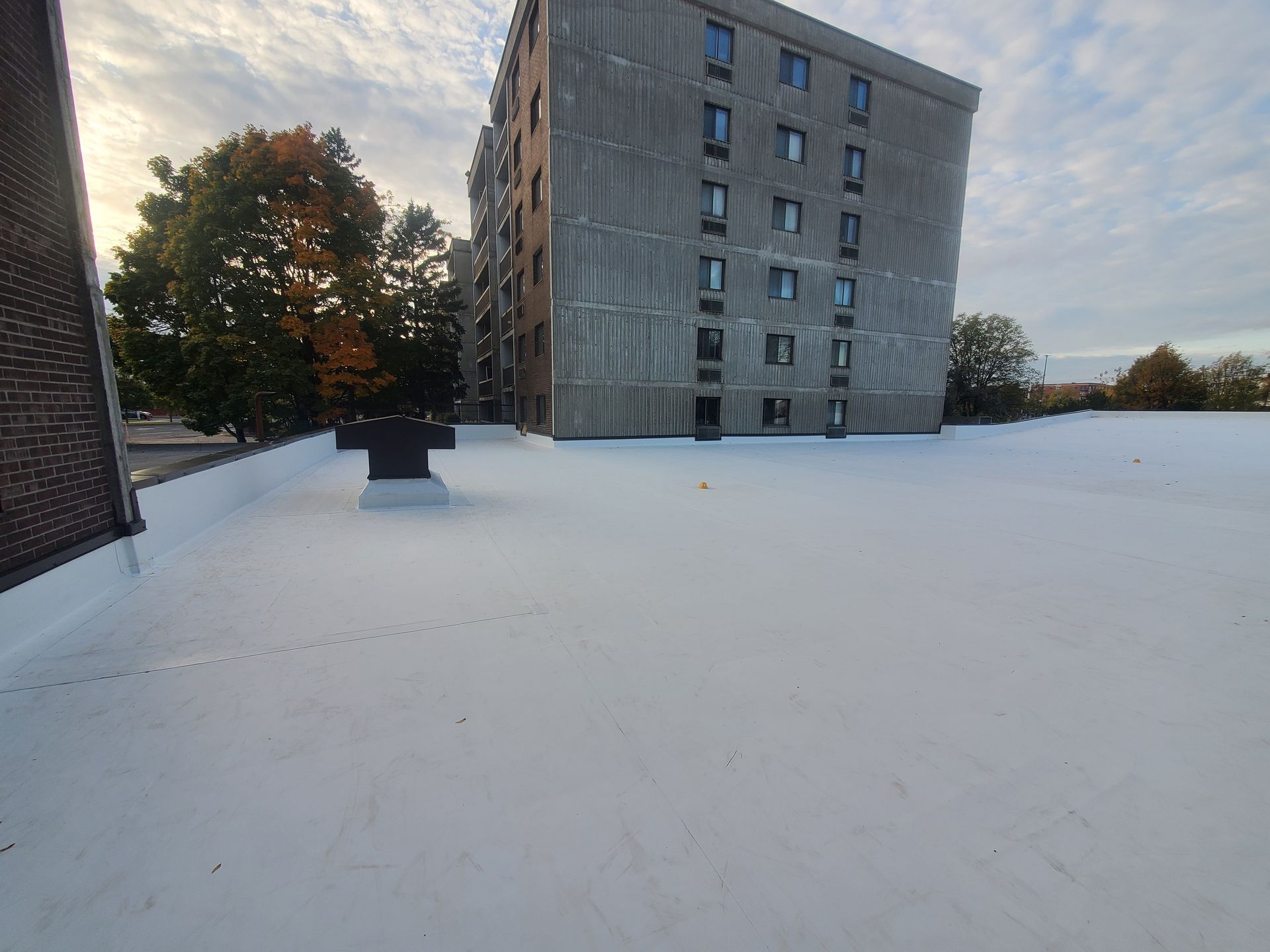 Un grand bâtiment avec un toit blanc et des arbres en arrière-plan.