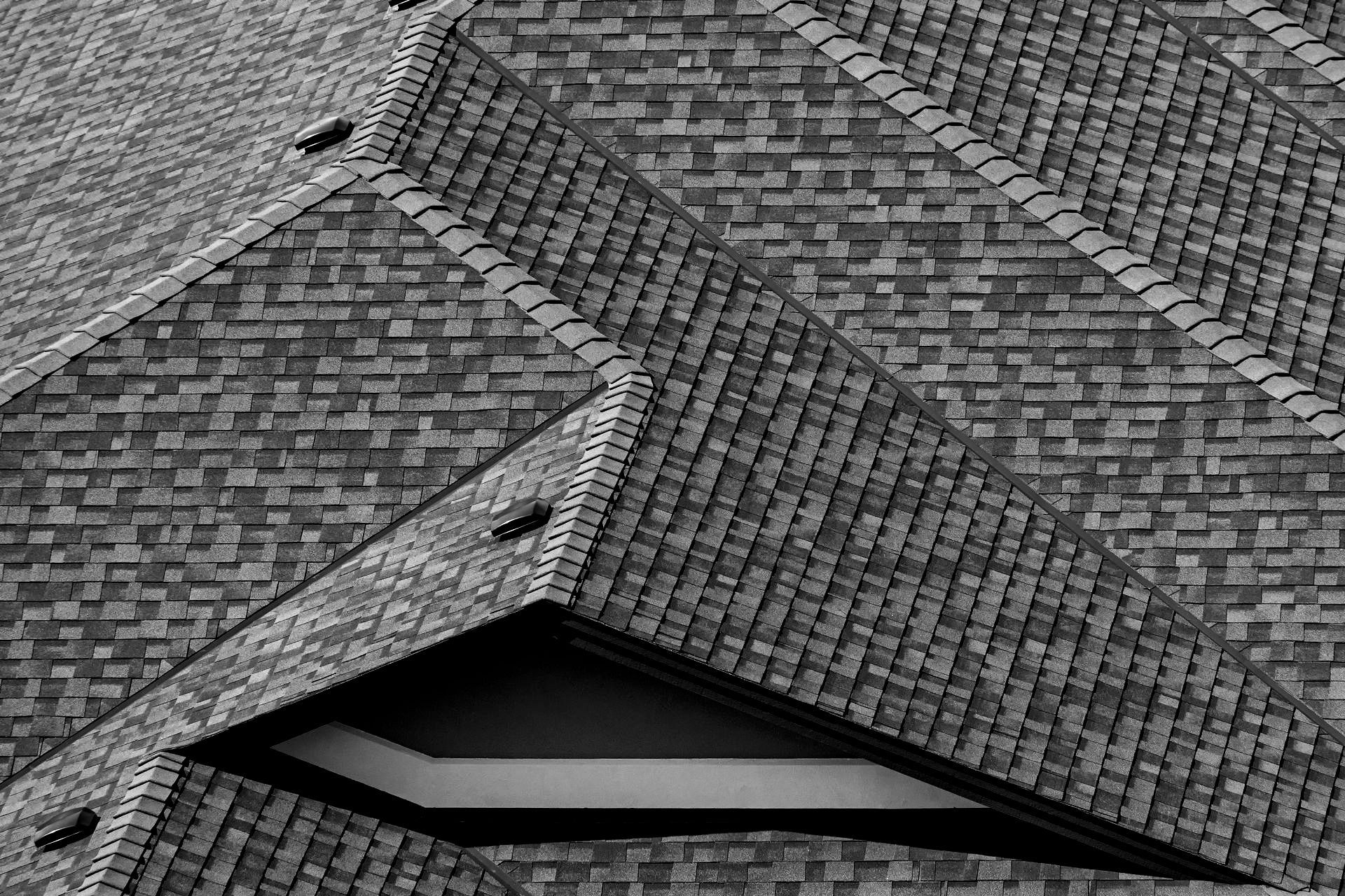 Une photo en noir et blanc d'un toit en briques avec une fenêtre.