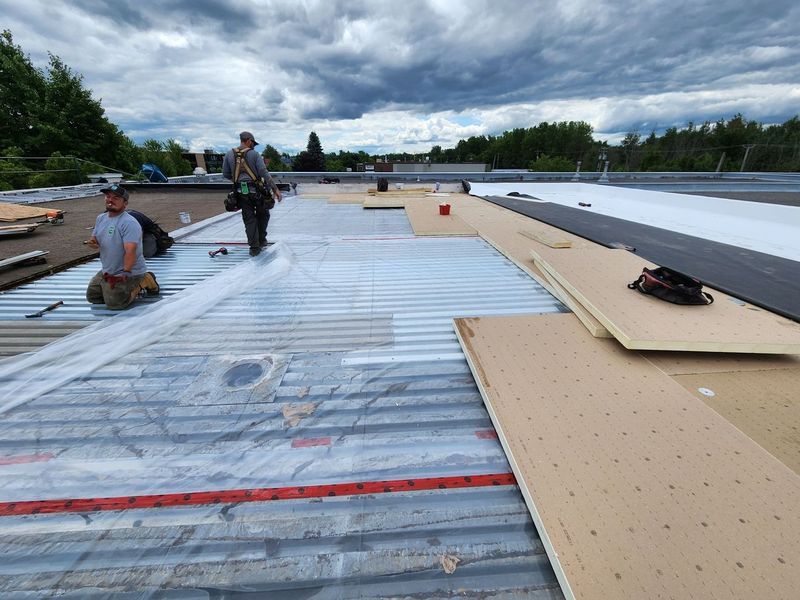 Two men are working on the roof of a building.