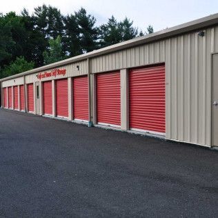 a row of storage units with red roller doors .