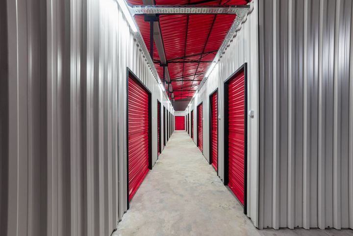 a long hallway with red doors in a storage facility .